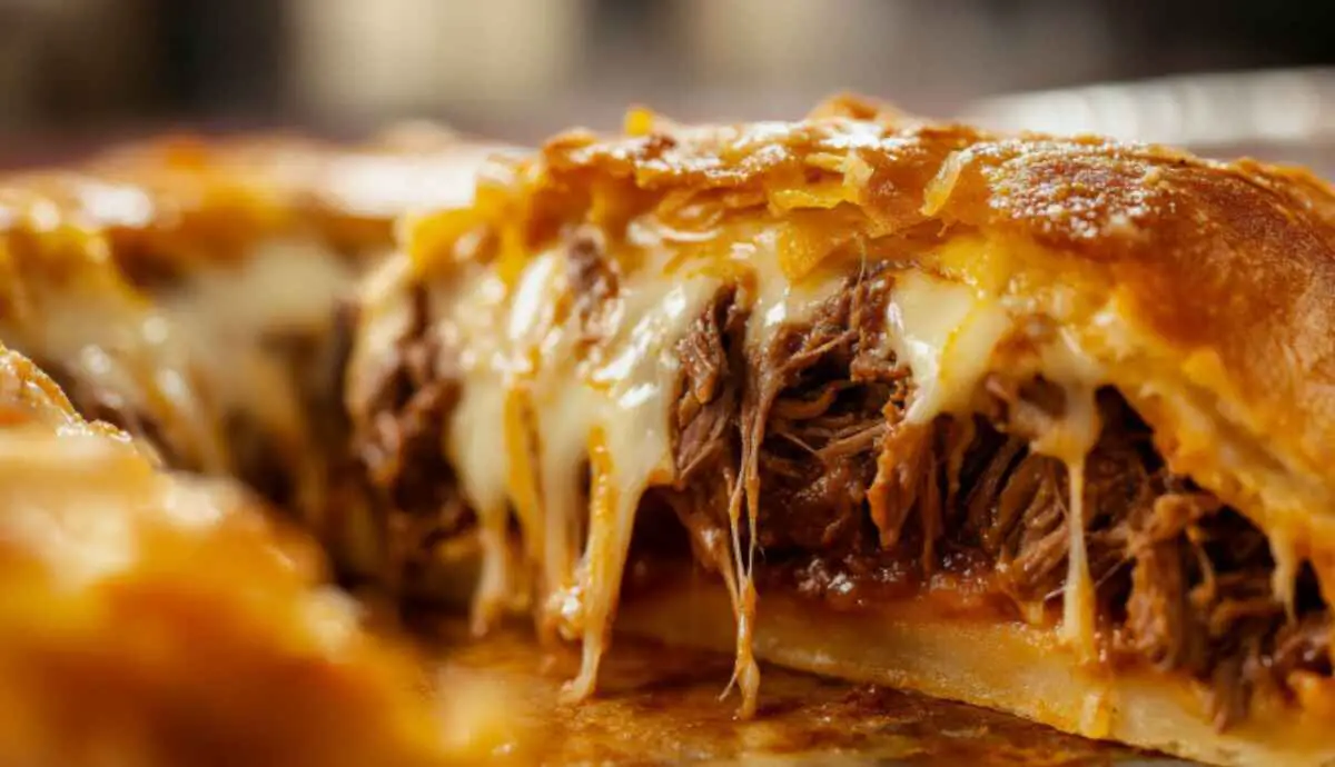 Cross-section of a birria bomb showing beef birria filling and melted cheese inside golden dough.