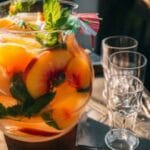 Pitcher of peach beach drink with fruit and mint garnish, party-ready
