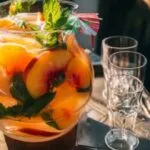 Pitcher of peach beach drink with fruit and mint garnish, party-ready