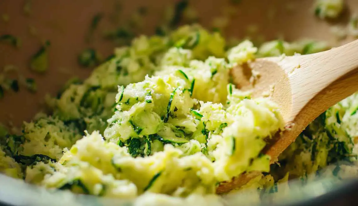 Grated zucchini being mixed into cake mix batter for a moist zucchini bread.