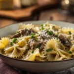 a Close Up Bowl Of Creamy Mafaldini Pasta With Sausage And Mushrooms, Garnished With Parsley.